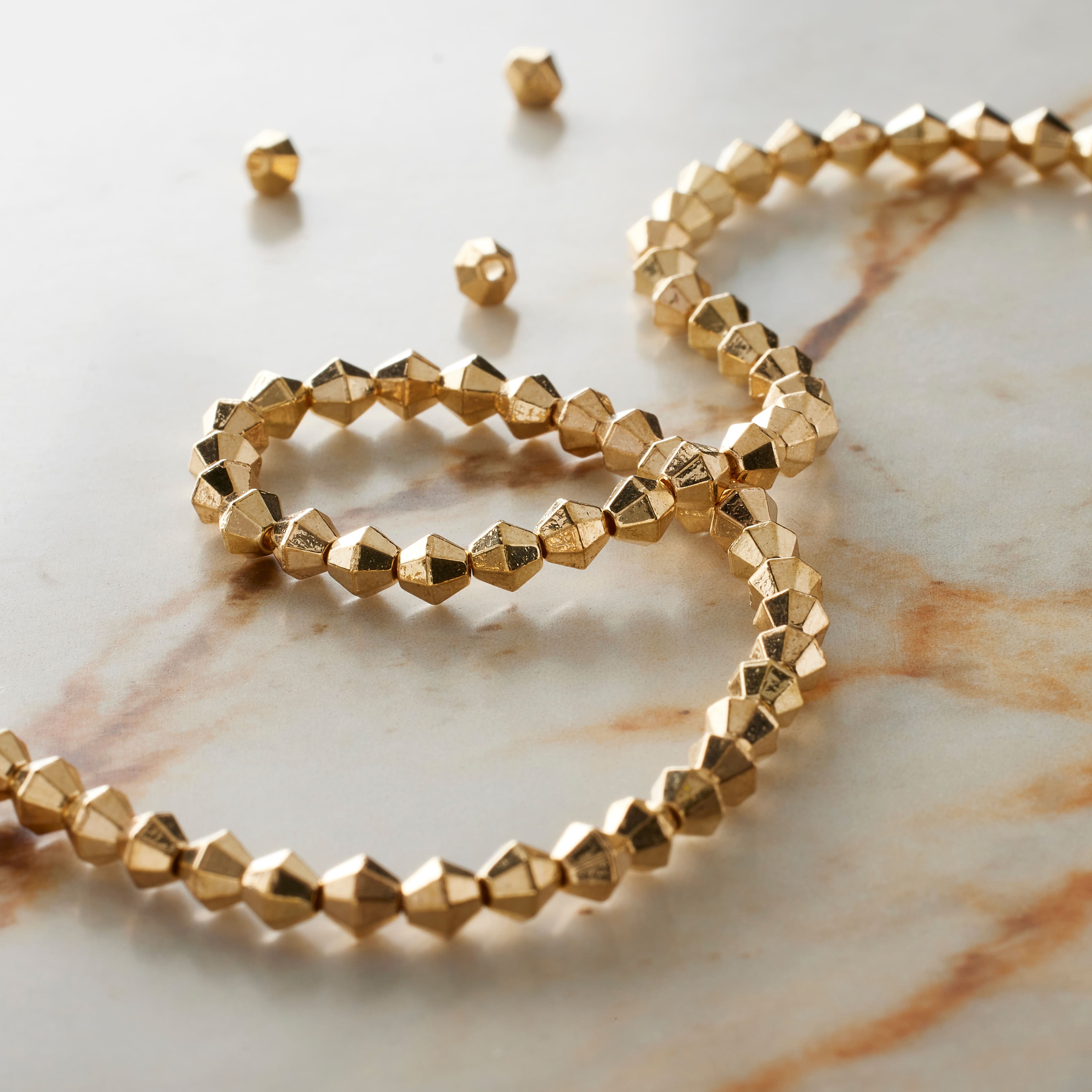 12 Pack: Gold Metal Faceted Bicone Beads, 4mm by Bead Landing™