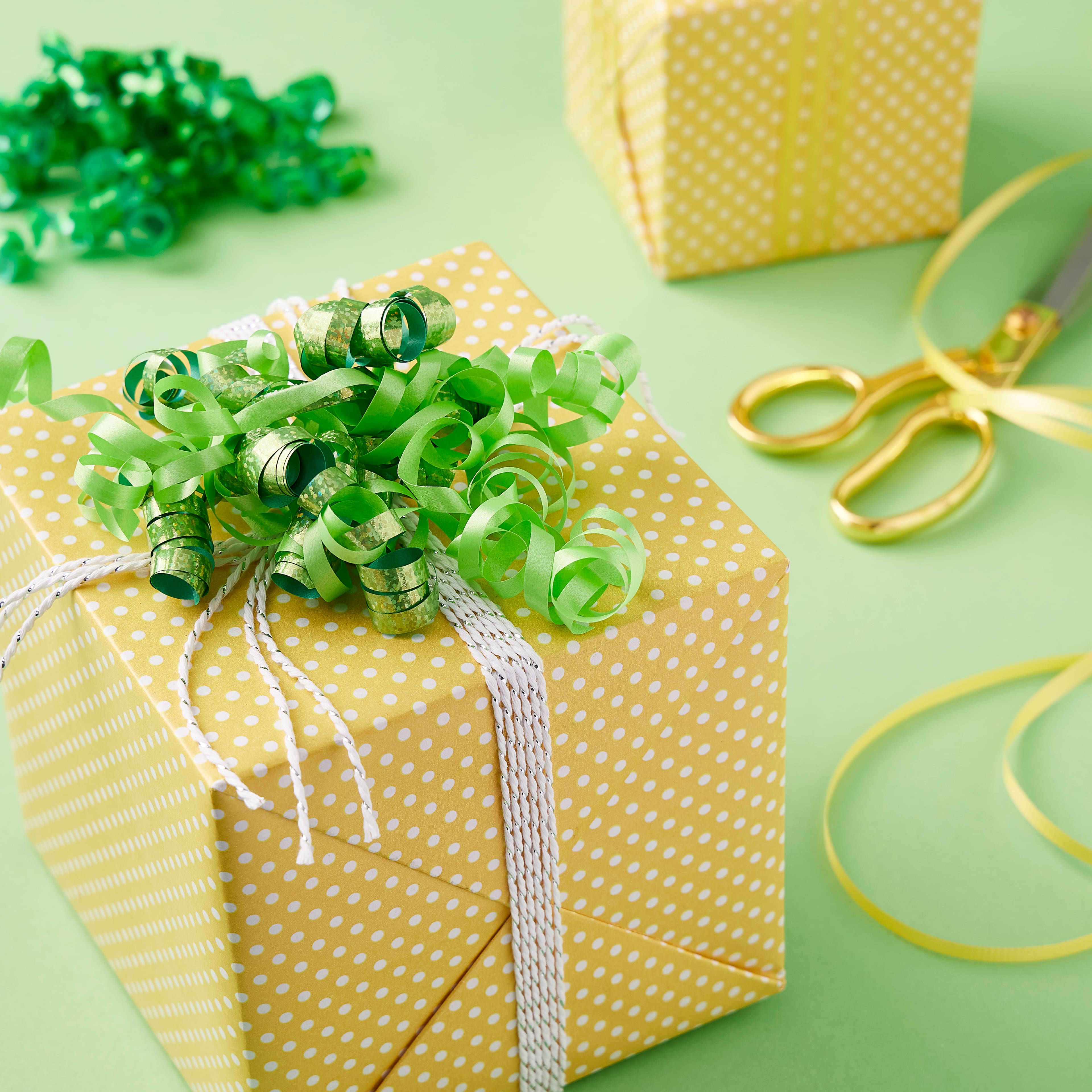 Curly, glittery green ribbon for gift wrapping on a white